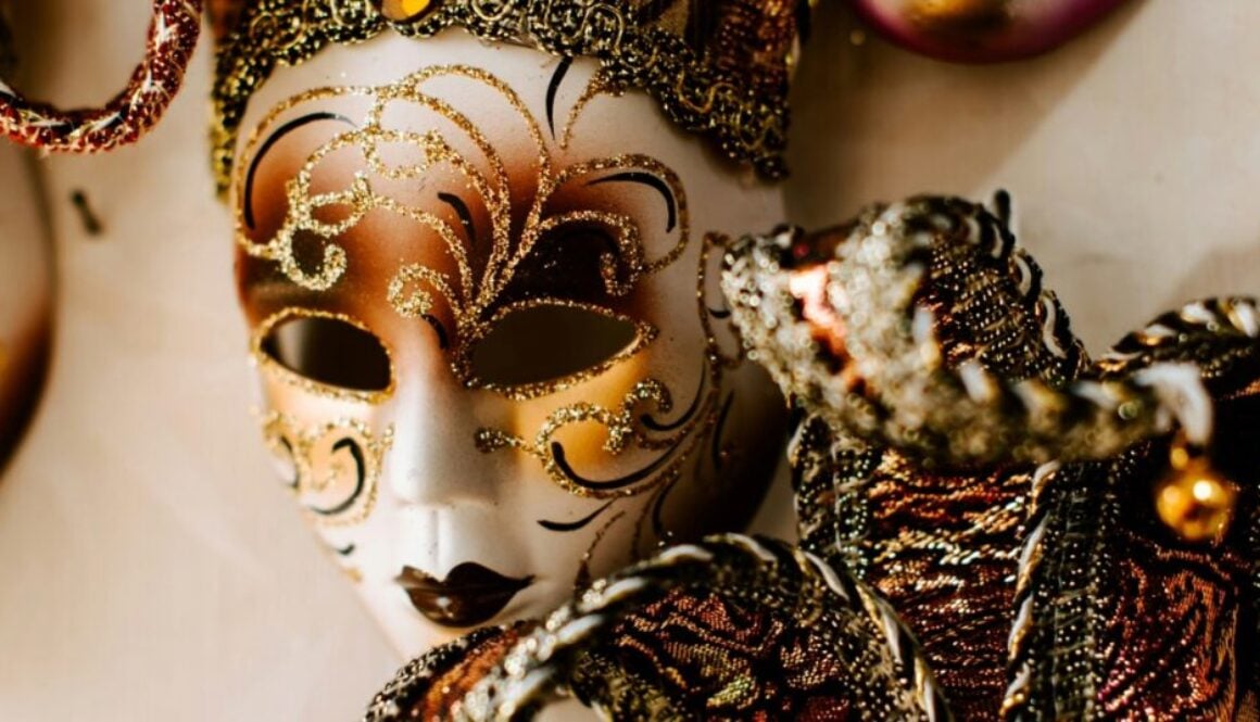 An ornate theatrical mask decorated with fold glitter and fancy ribbons.