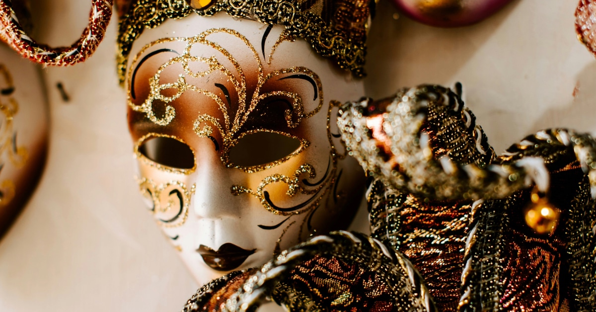 An ornate theatrical mask decorated with fold glitter and fancy ribbons.