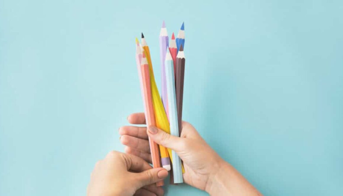 hands holding a bunch of colored pencils
