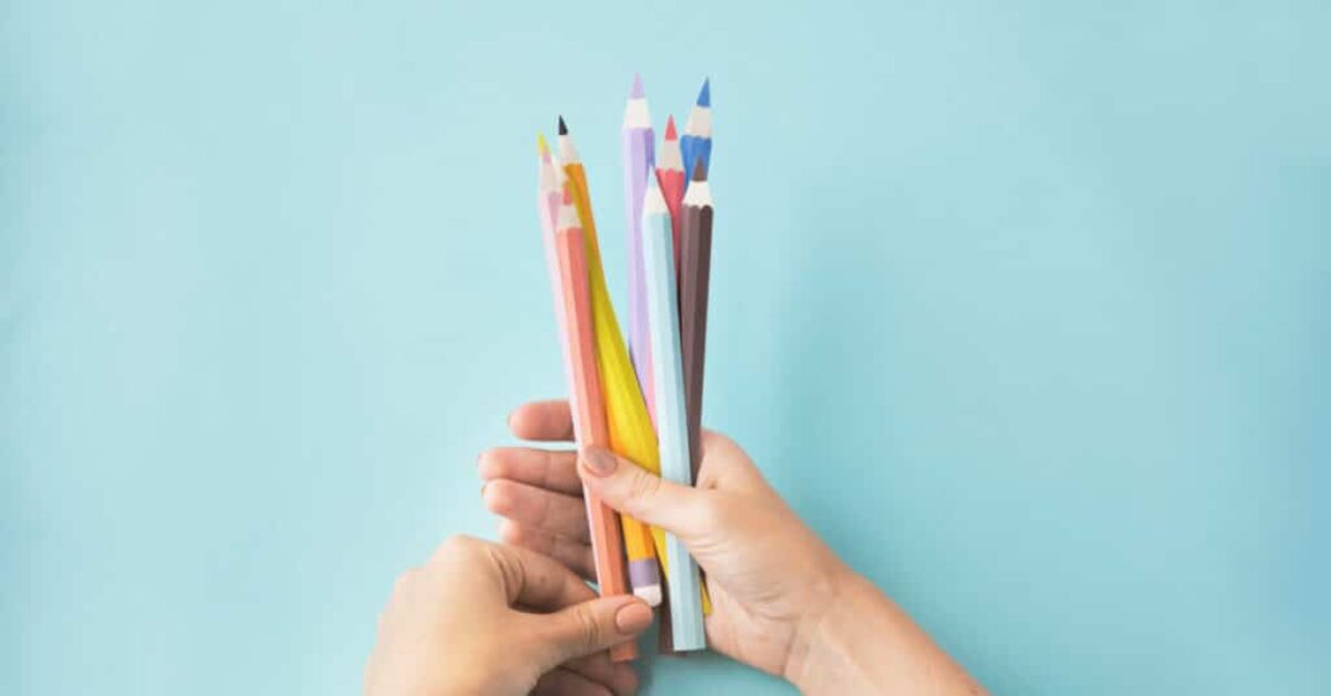 hands holding a bunch of colored pencils