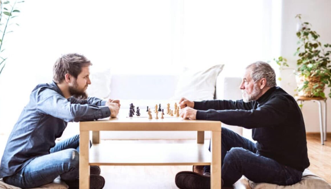 two men sitting on the floor staring at each other while playing chess