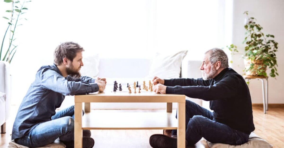 two men sitting on the floor staring at each other while playing chess