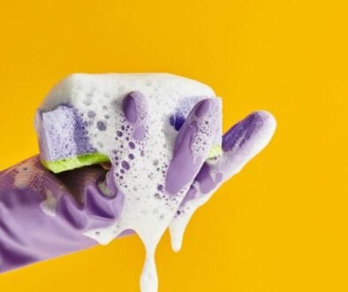 a hand wearing a rubber glove holding a soapy sponger
